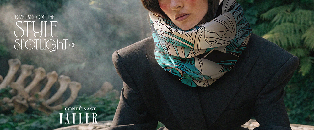 photo of woman wearing padded shoulder black suit with large scarf around neck, printed in colourful maxi print in green blue and teal. printed textiles, boutique wholesaler supplier, United Kingdom