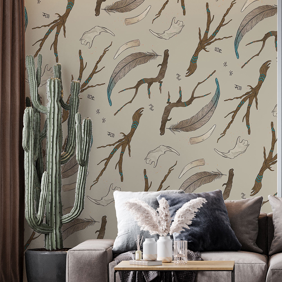 illustration of pattern on cream background of branches, feathers, bones, teeth, runic symbols, gold splatter, aura lines, arranged diagonally. Pattern applied on a wallpaper mockup of a living room with light colour sofa, cushions, cactus on left corner.