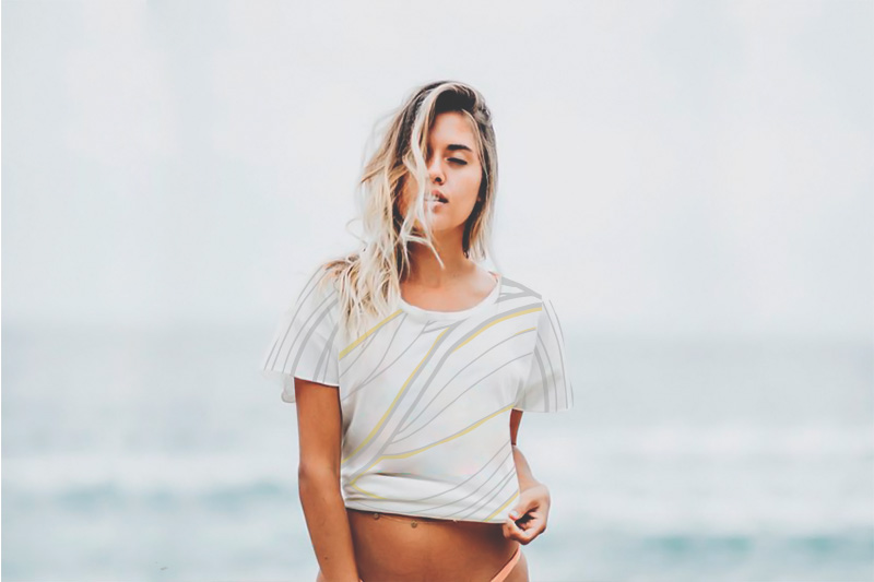 Girl posing eyes closed blonde long hair. Cropped printed shirt, with light grey and yellow lines.